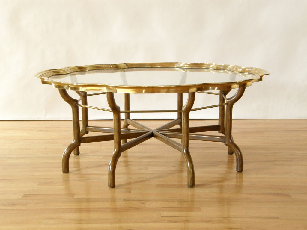 Unusual Baker coffee table with sculptural wood base and brass rimmed glass top. An oversized play on the traditional serving tray table.