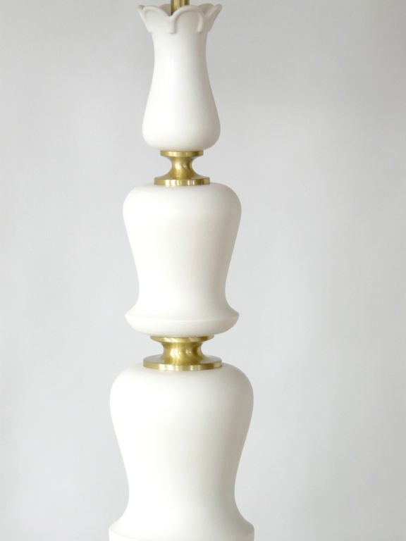 This circa late 1950s table lamp is made of stacked, curvy shaped porcelain forms separated by brass fittings. It was designed by Gerald Thurston for Lightolier.

The shade pictured on the lamp is for display purposes only. It is not included. 
For