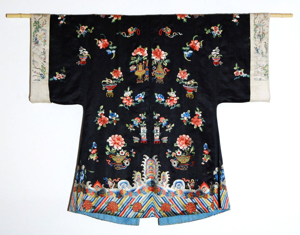 Chinese woman's unofficial Summer robe with silk embroidered potted peonys, peach blossoms with fruit, and crashing waves at the bottom.  The sleeve linings feature women in a garden landscape with pavillions and scholars' rocks.<br />
<br