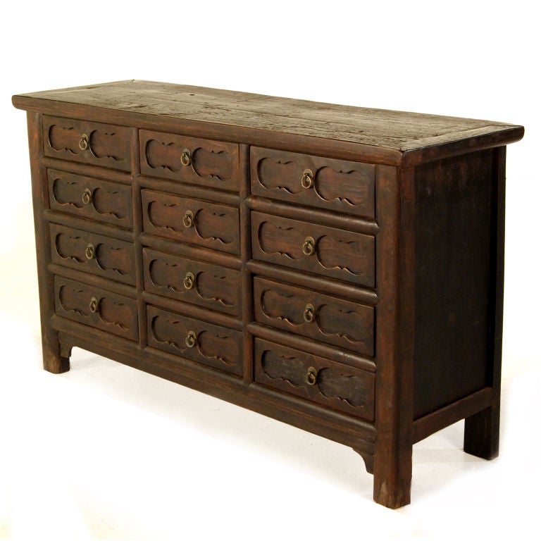 A 19th century elmwood chest with 12 drawers with carved fronts and brass hardware from provincial China.  Pair available, priced individually.<br />
<br />
Pagoda Red Collection #:  W115<br />
<br />
<br />
Keywords:  Chest of drawers,