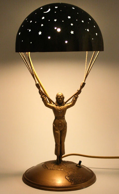 This is an unusual and rare lamp, depicting Amelia Earhart underneath a parachute of stars standing on top of the world.