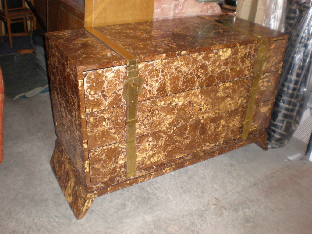 An elegant and unusual chest of drawers clad in crushed coconut with buckle straps as hardware. splayed legs.