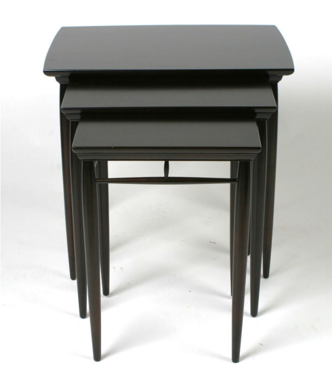 Set of 3 nesting tables in walnut with dark brown finish. tapered conical legs with cross stretchers. Largest table 23