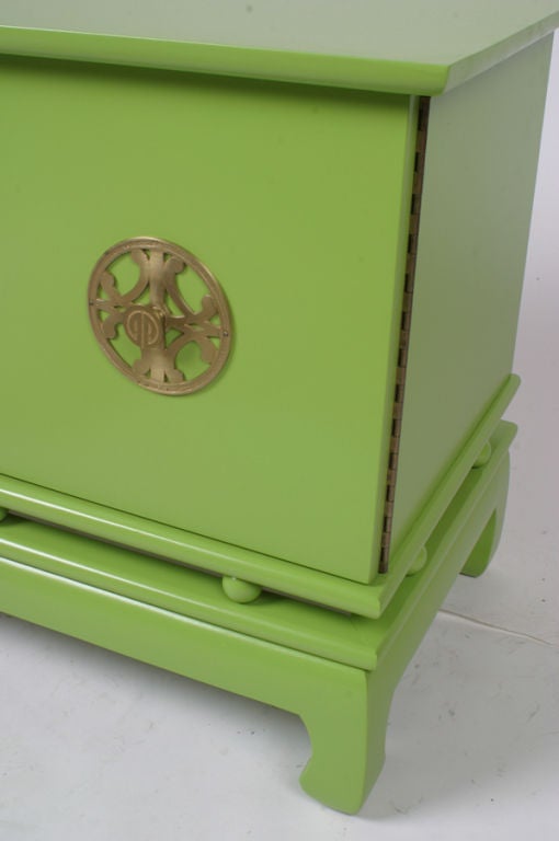 Pair of  stylish midcentury green lacquer bedside cabinets. Cabinet with two doors sits on floating balls with asian influenced base. Brass hardware. Featured in Architectural Digest New price is net.