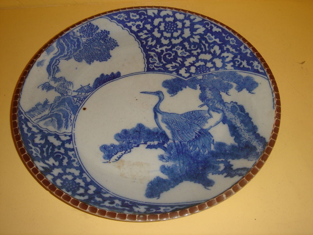 Blue and white ceramic Japanese charger with detailed pie crust edge in dark rust red color