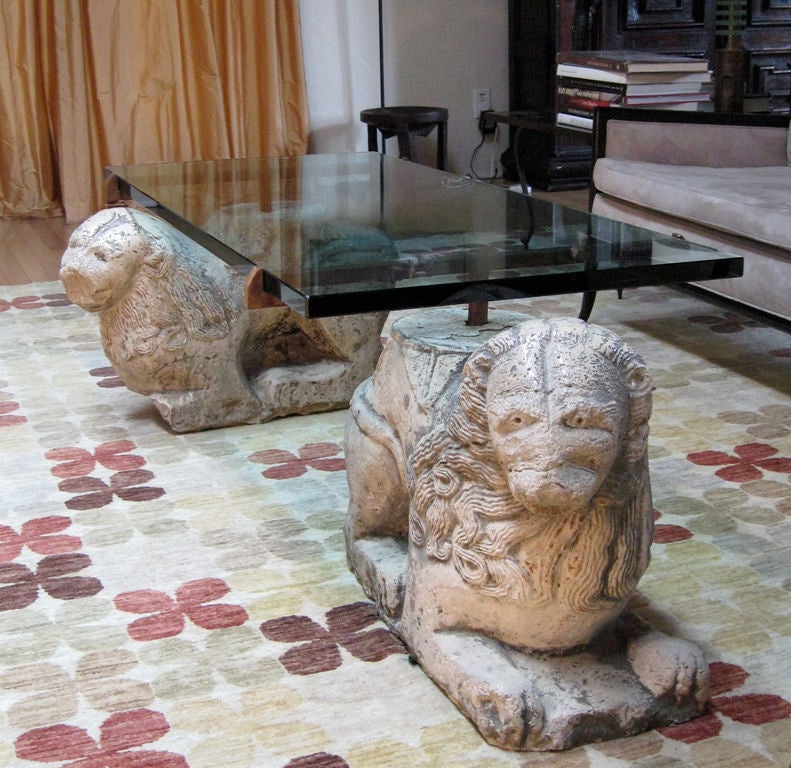 A magnificent glass top coffee table raised by two rare 12th century Venetian marble lions.