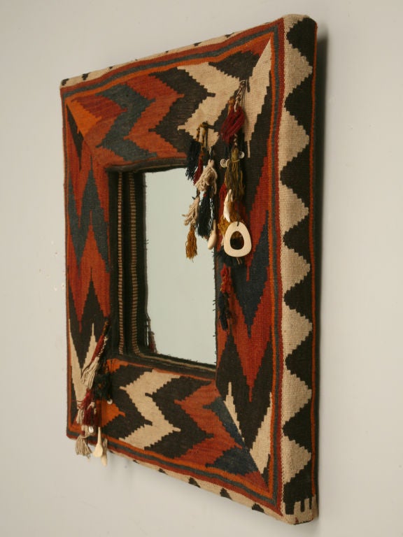 Kilim mirror hand-decorated by an old hippie with bone, teeth, heishi beads and finished off with tassels. The kilim was originally a rug that had holes too bad too repair. In order to salvage the rug we used it for mirrors, seat coverings and other