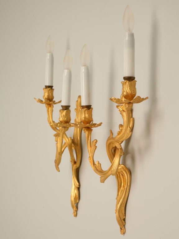 Breathtaking pair of vintage French, Doré bronze Louis XV style two light sconces with their original glass candle covers. These sconces are absolutely stunning. They have been completely rewired for the USA by our in-house electrician.
