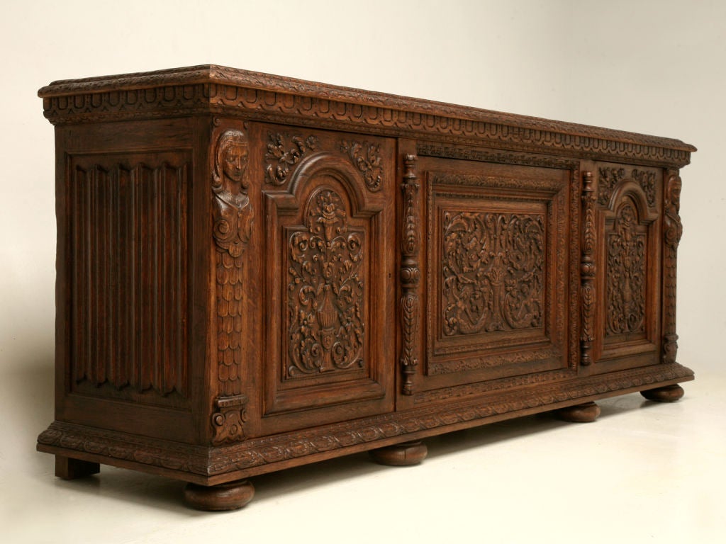 Vintage heavily hand-carved Spanish oak 3 door buffet with mermaid motifs, linen-fold end panels, and fitted with 2 dovetailed drawers, one behind each end door. Once you touch and really examine this buffet, you would swear it was from the 1800's,