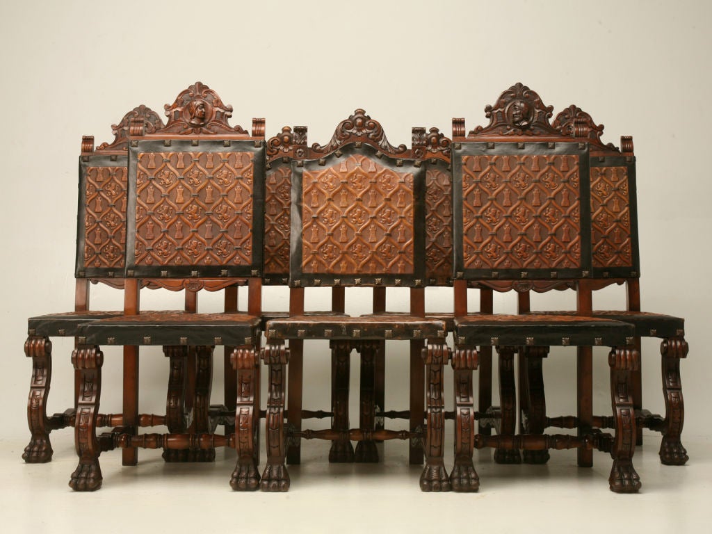 Unmatched set of ten hand-carved Spanish mahogany dining chairs. A wonderful set of 8 sidechairs (4 each of two slightly different styles) with unique matching hand-tooled leather upholstery, together with 2 awesome matching throne chairs with arms.