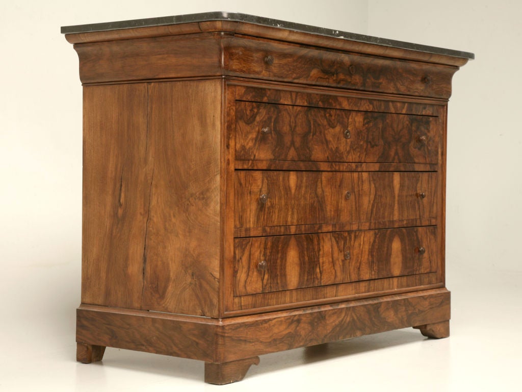 Marvelous antique French bookmatched burled walnut Louis Philippe commode with four beautifully hand-dovetailed drawers, fantastic wood escutcheons and pulls, too. A majestic black marble top adds contrast to this phenomenal commode. A great find.