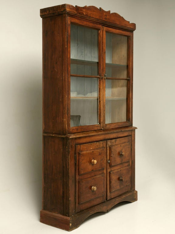 Breathtaking, primitive antique English Georgian pine glazed cabinet. This striking piece has it all, from its wonderful cherry exterior patina, to its original paint interior,all the way to its original wavy glasses, this is an amazing cabinet.