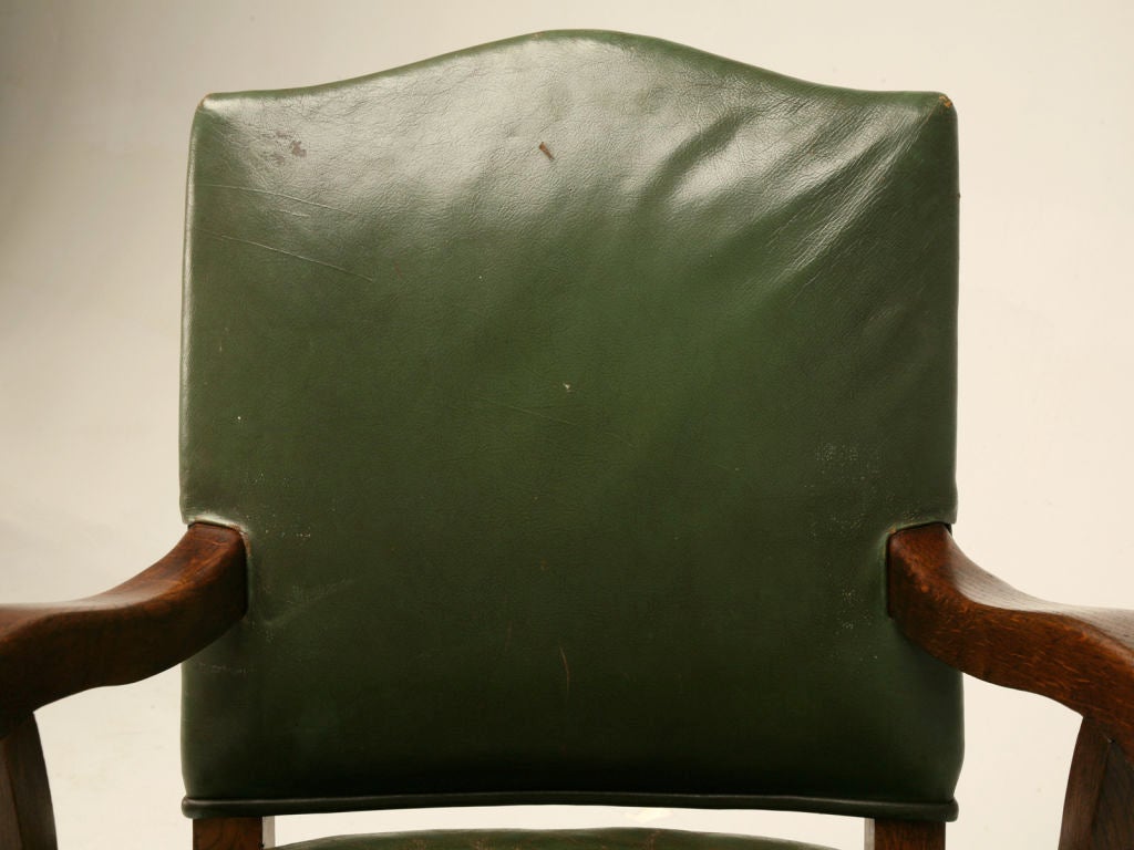 Vintage English oak desk chair with arms and hunter green leather upholstery.