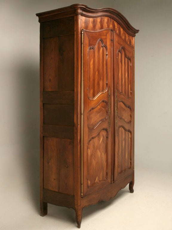 French Louis XV bonnet-topped armoire constructed completely of wild cherry. This amazing showstopper has incredible attention in its details, an oystered frieze along with the intricate herring bone design that sets this armoire apart. If you are