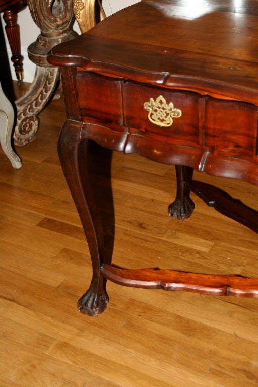 A Dutch Colonial South African Baroque style Laurel wood (stinkwood*) table with four cabriole legs terminating in ball and claw feet; joined by a stretcher and having a carved shaped apron; finished on four sides and with three drawers having
