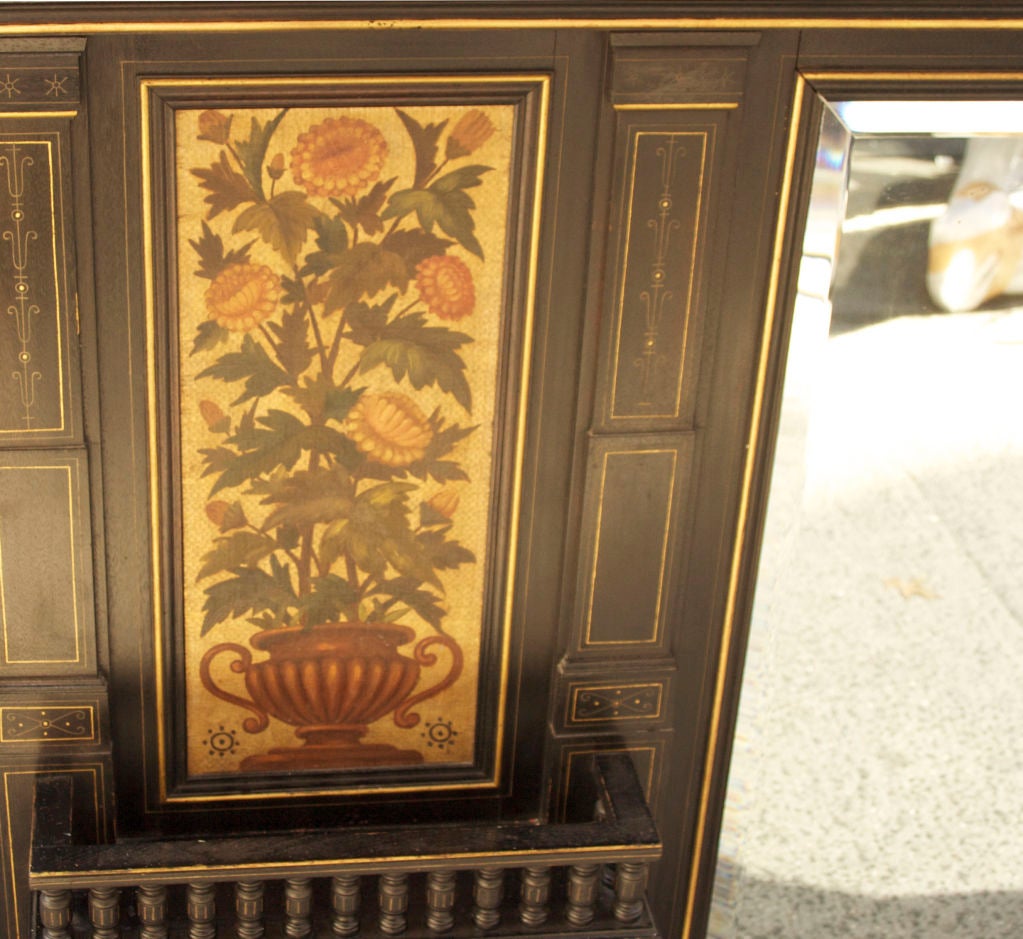 An English Aesthetic Movement over mantle mirror with ebonized frame, having contrasting satin wood stringing and horizontal frieze with hand-painted floral motifs and vertical panels; the vase issuing floral bouquets above shallow bracket shelves