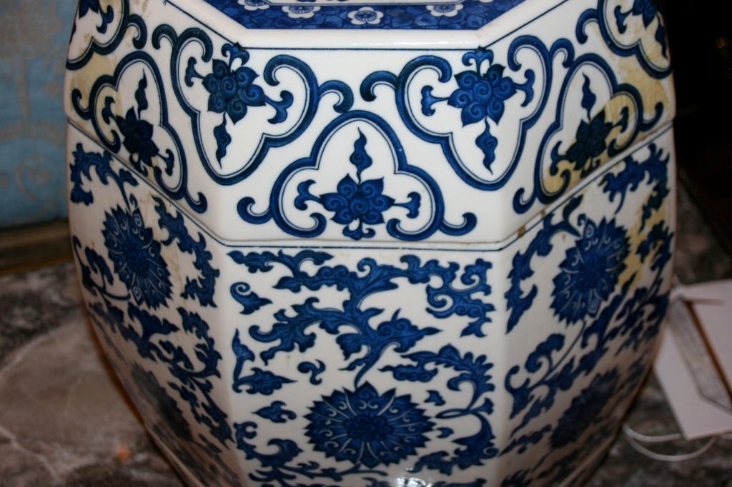 A pair of octagonal Chinese garden stools with traditional blue floral decoration on a white ground and with pierced coin motif on flat top.
