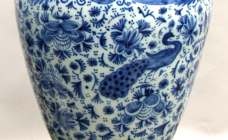 A pair of Dutch Delft vases with traditional blue decoration on a white ground, depicting peacocks amidst flowers and foliage. Now on turned wooden base with water gilt edges.