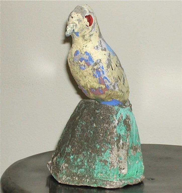 From a collection of Adam Pfaltzgraff animal garden ornaments. The trade mark glass eyes are intact on this folk art bird.The bird shows traces of yellow, blue and brown paint. The base has retained much of the green surface.