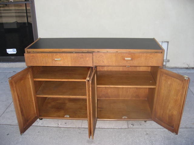 Lovely four door cane buffet on wheels with two drawers and vinyl covered top.  Three shelves provide ample storage space and one drawer has a removable divider.