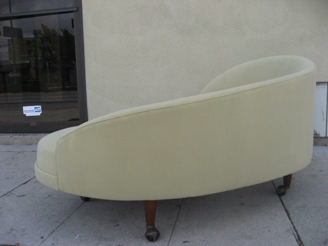 Rounded boudoir chair with cascading back rest.  Covered in suede and the legs are on casters.