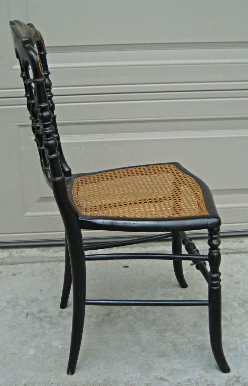 Gorgeous set of four Ebonized Chiavari chairs with hand caned seats.  Gold decorative painting on legs and seatbacks.  These chairs are the early hand-crafted wood models.  Similar models shown in the final photo in the Dining Room of Prince and