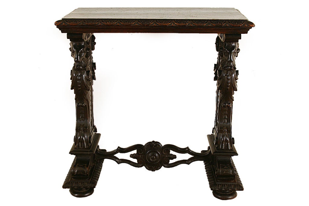 The rectangular roundel moulded top above two trestle supports, each ornately carved with ram's heads, foliage, and volutes, having a pierced and carved stretcher and resting on compressed bun feet.