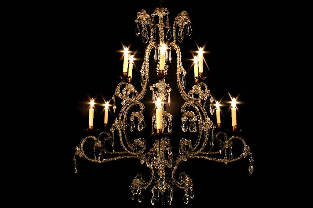 of generous proportion, the central iron rod supporting 12 arms each with two levels of bobeches, the arms composed of a series of s and c scrolls and having alternating blown and pressed glass bead chains mounted to each side, decorated throughout
