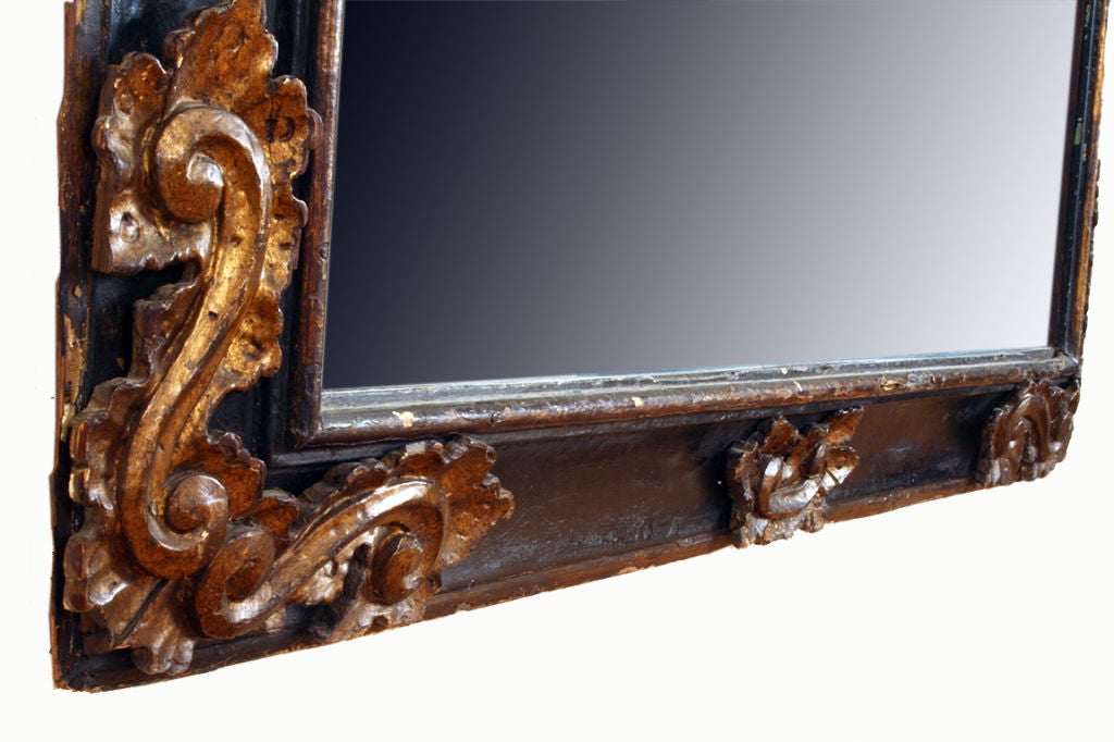 the frame of graduated form and descending in height from middle to end, ebonized, with detailed carved giltwood corners and trim at top, bottom and sides, retaining two original vertical iron hanging loops