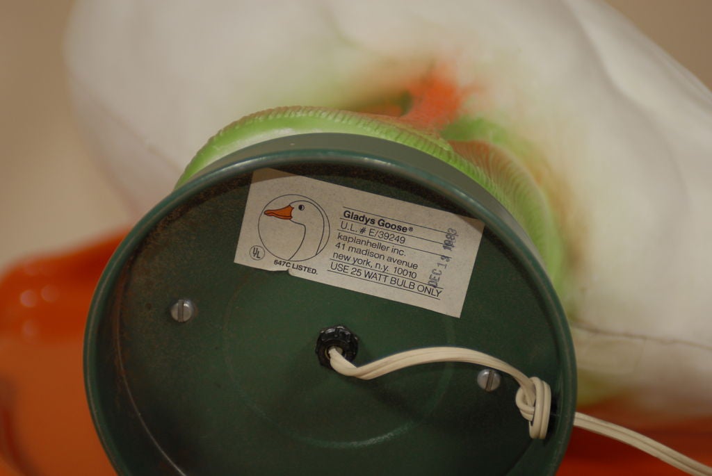 A highly entertaining lamp of polychrome form in the shape of a goose, lit from the inside and resting on a green painted metal base.  Bearing the manufacturer's label, which is stamped 