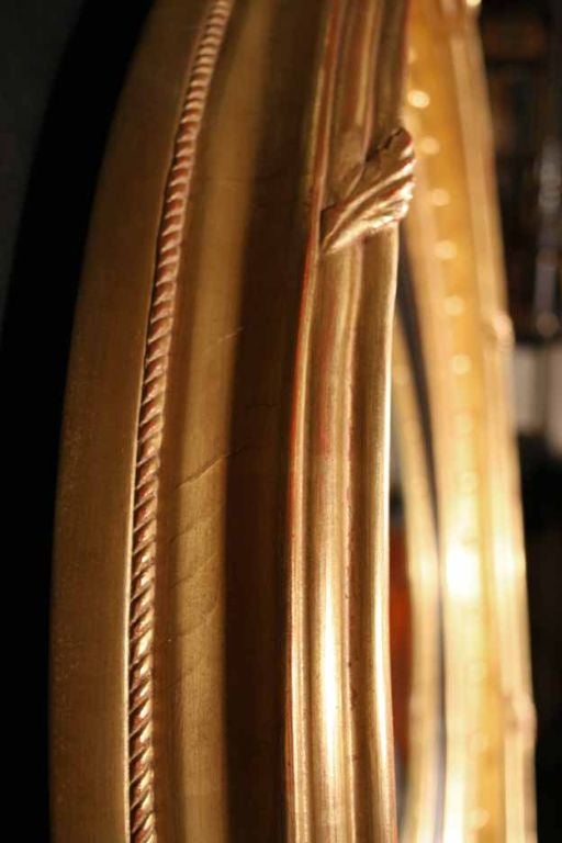 Bold Regency gilt wood convex mirror. The circular mirror plate surrounded by a ribbed ebonized filet molding and deeply molded gilt frame enriched by a carved ball decoration. <br />
Bearing an old label  on the reverse “Jackson #5 Essex Bridge,