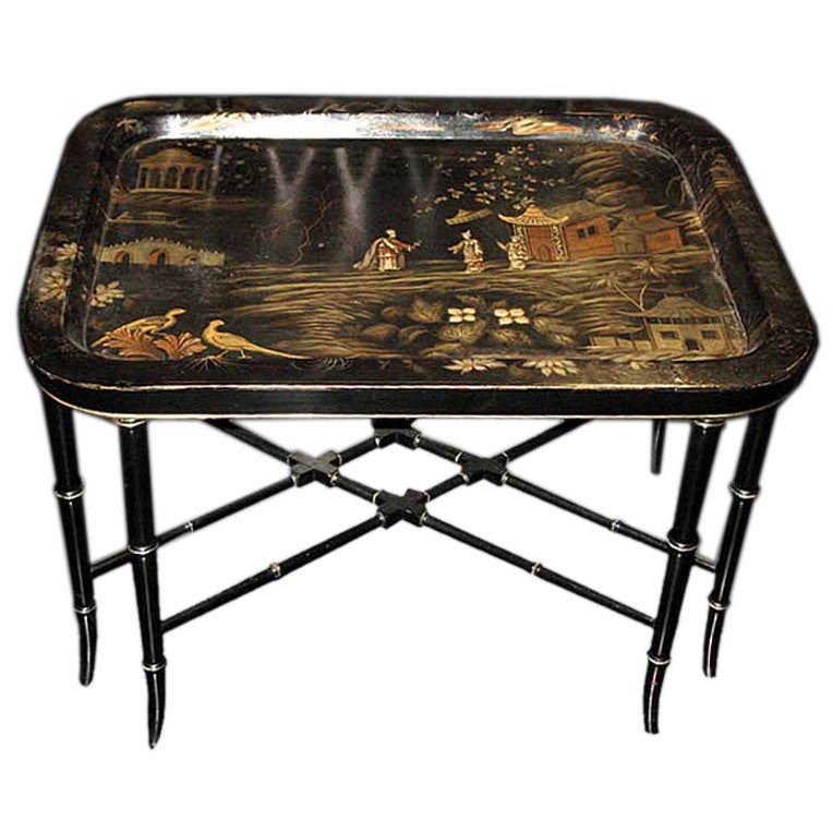 # S009 - chinoiserie black lacquered papier mâché rectangular tray table. The raised edge and central panel painted with a chinoiserie landscape scene depicting pagoda, temples, follies, bridges, and figures in a garden setting. Raised on a black