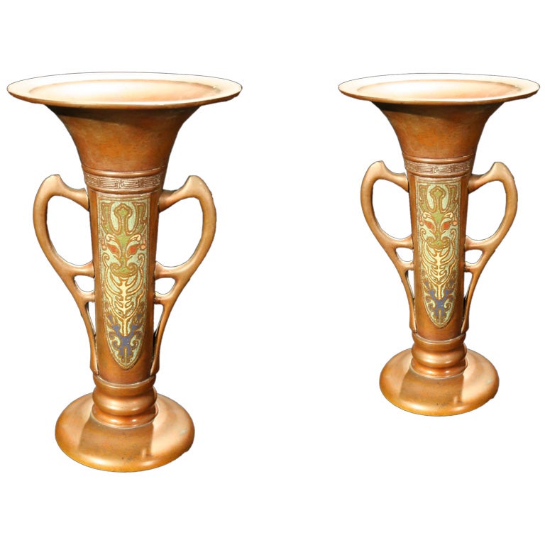 # S040. Pair of Chinese bronze and parcel-gilt champlever urns richly decorated with polychrome enamel colors. The elongated round form with flare necks and decoratively shaped handles and round plinth bases. Champlever is a style of enamel