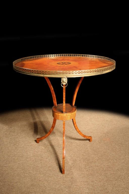 # S515 -  Dutch satinwood and mahogany table enriched by brass details and decorative inlays. Inspired by the designs of Thomas Sheraton (pub. 1803), the round top centers a marquetry medallion with fan radiating veneers and a  chequer strung border