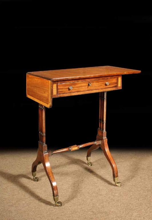 # S121 elegant George III drop-leaf table executed in mahogany and enriched with satinwood inlays. The rectangular top with crossbanded borders above a frieze with one drawer. All raised on a trestle base with a connecting stretcher embellished with