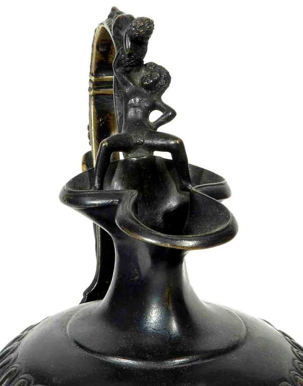 The high scrolled handle decorated with figures, grapes and a putti above a trefoil lip and gadrooned body raised on a circular socle and plinth.