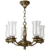 A five-arm brass chandelier with hurricane shades