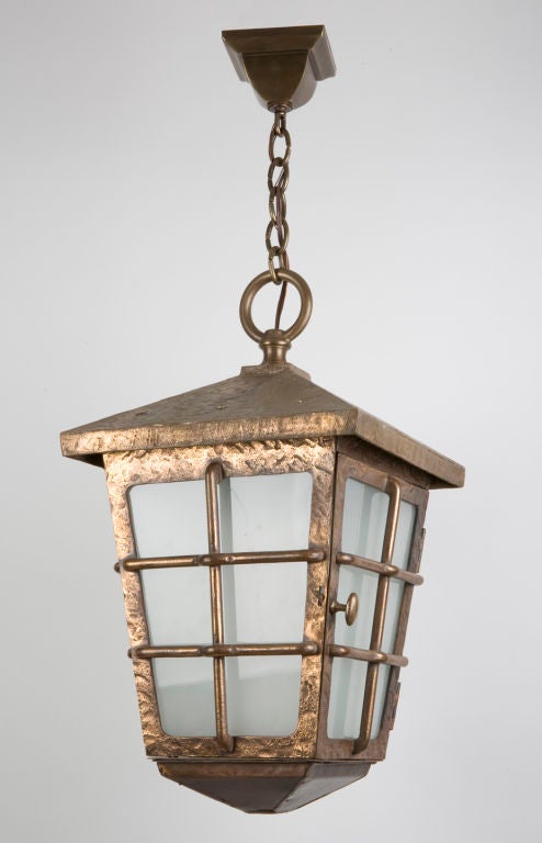 A large hammered bronze lantern with frosted glass.