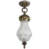 A beveled glass pendant with foliate brass hardware