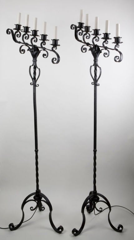 TF1702<br />
A pair of blackened wrought iron floor lamps with tripod bases.<br />
<br />
Overall height: 66