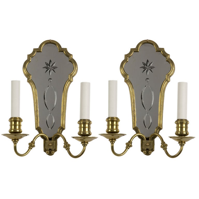 A pair of two arm brass mirror back sconces