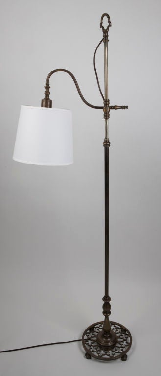 TF1769<br />
A cast brass adjustable height, bridge-arm floor lamp with an openwork, quatrefoil motif base, in its original age darkened finish.<br />
<br />
Overall height: 62-1/2