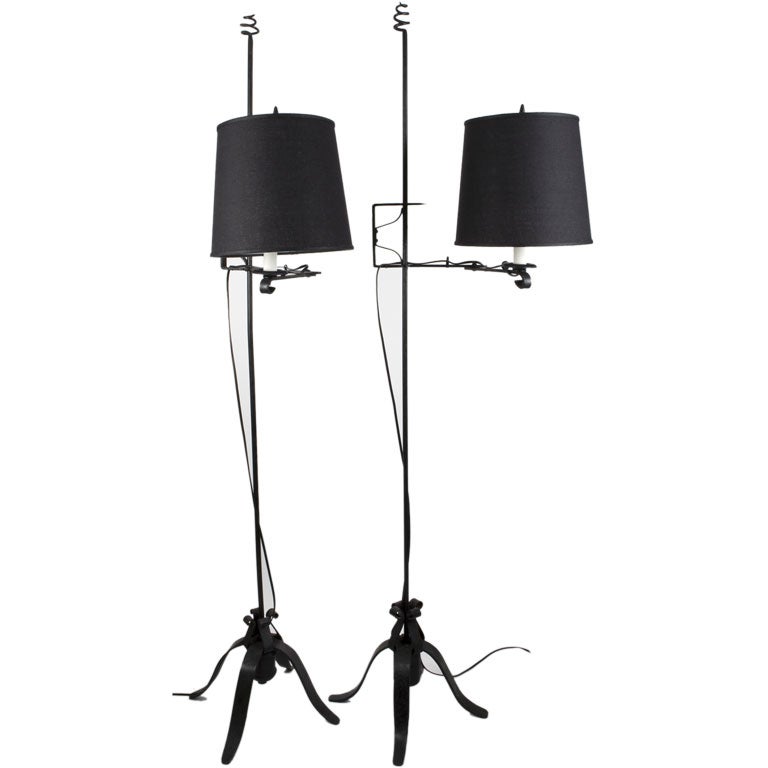 A pair of black wrought iron swing arm floor lamps