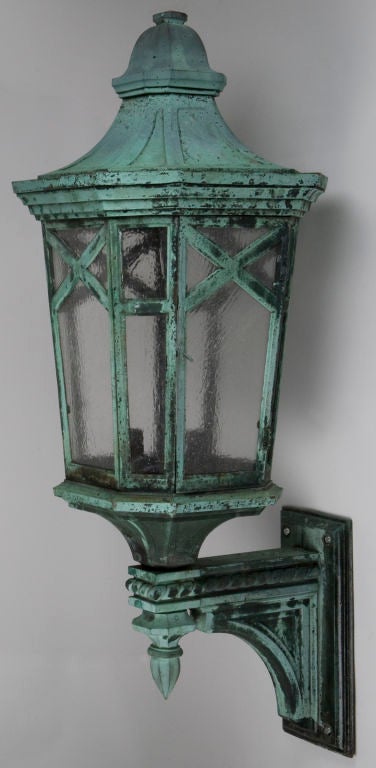 EX0552<br />
A pair of large bronze octagonal wall lanterns in their original weathered verdigris patina, glazed with textured clear panes. Lamp access is via a hinged door. Lamp access is via a hinged door. From a Philadelphia bank building.<br