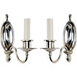 A pair of single arm silver sconces