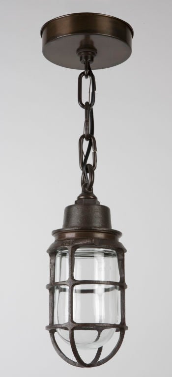 AHL3034<br />
A blackened bronze cage pendant fixture with a clear glass threaded lens. Signed by the maker Russell Stoll.<br />
<br />
Current height: 48-1/4