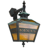 A verdigris copper exterior sconce with amber glass