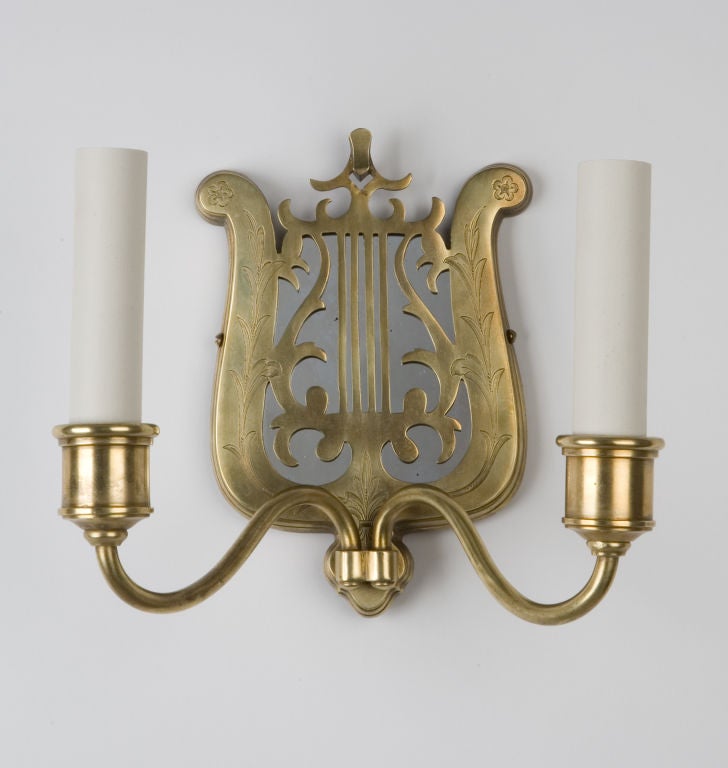 A pair of lyre-form, mirror-backed brass sconces