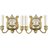 A pair of lyre-form, mirror-backed brass sconces