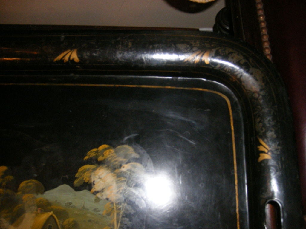 A painted and parcel gilt tole tray with painted landscape on a black background.<br />
21.5 deep, 30